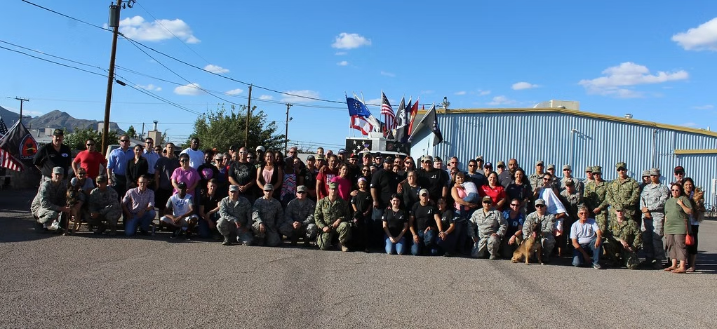 A military unit posing together for a group photo with a flag