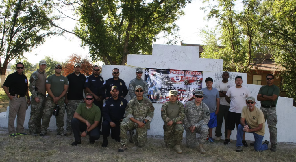 Service members gathered beside a memorial banner
